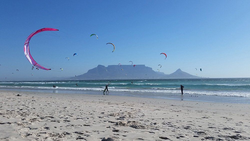 Kites über dem Kite Beach in Blouberg, dahinter der Tafelberg